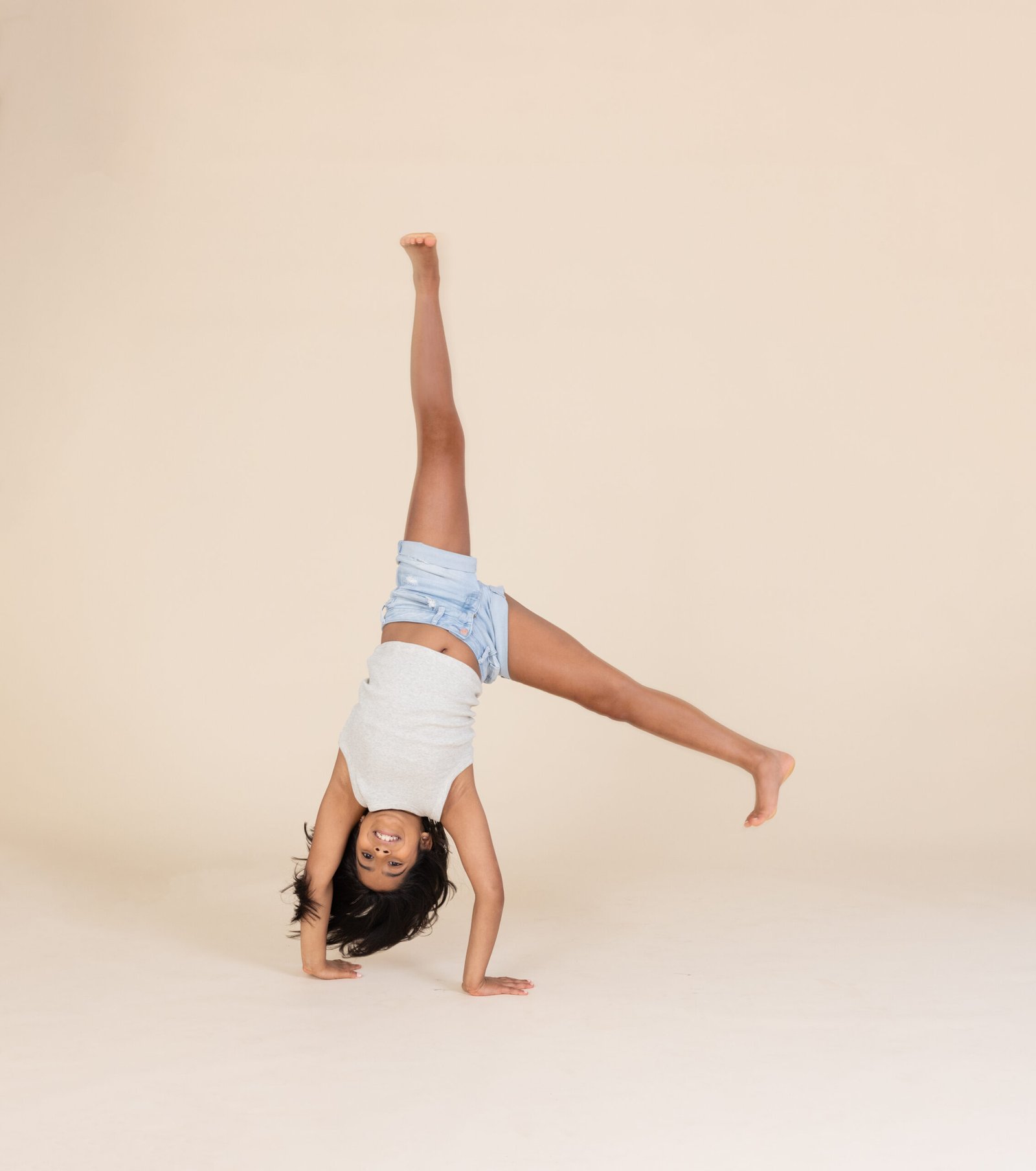 Young Indian American girl having fun and doing a cartwheel at Malone Portraits photo studio